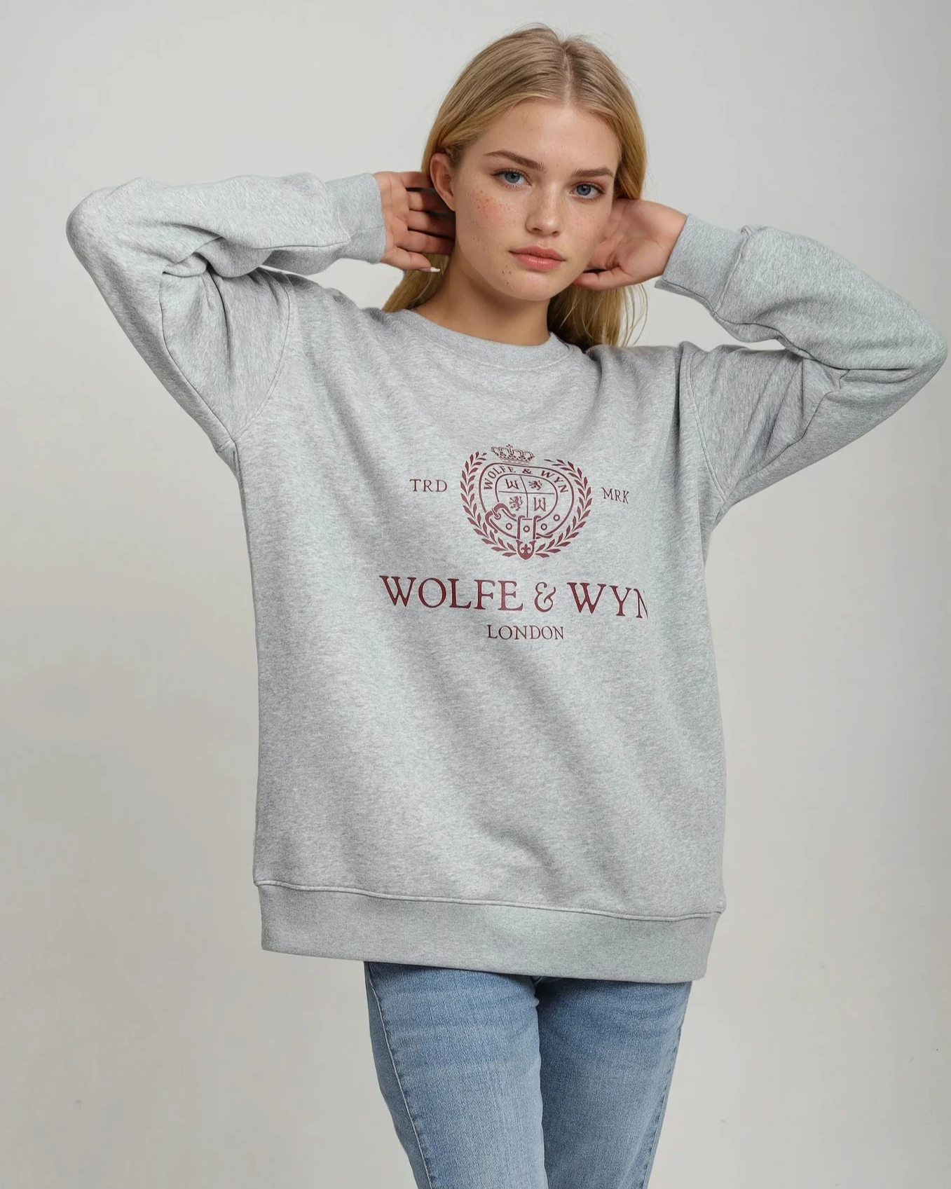 Person wearing a gray sweatshirt with 'Wolfe & Wya' branding on a plain background