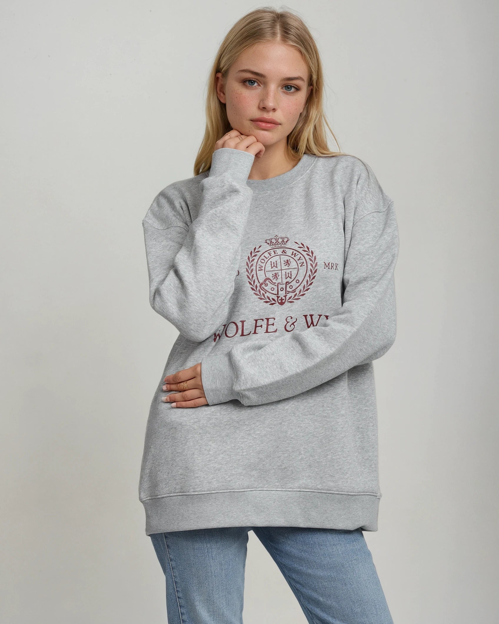 Person wearing a gray sweatshirt with a logo and text on a plain background