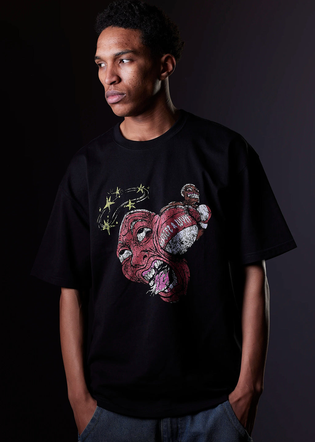 Person wearing a black t-shirt with a colorful graphic design on a dark background