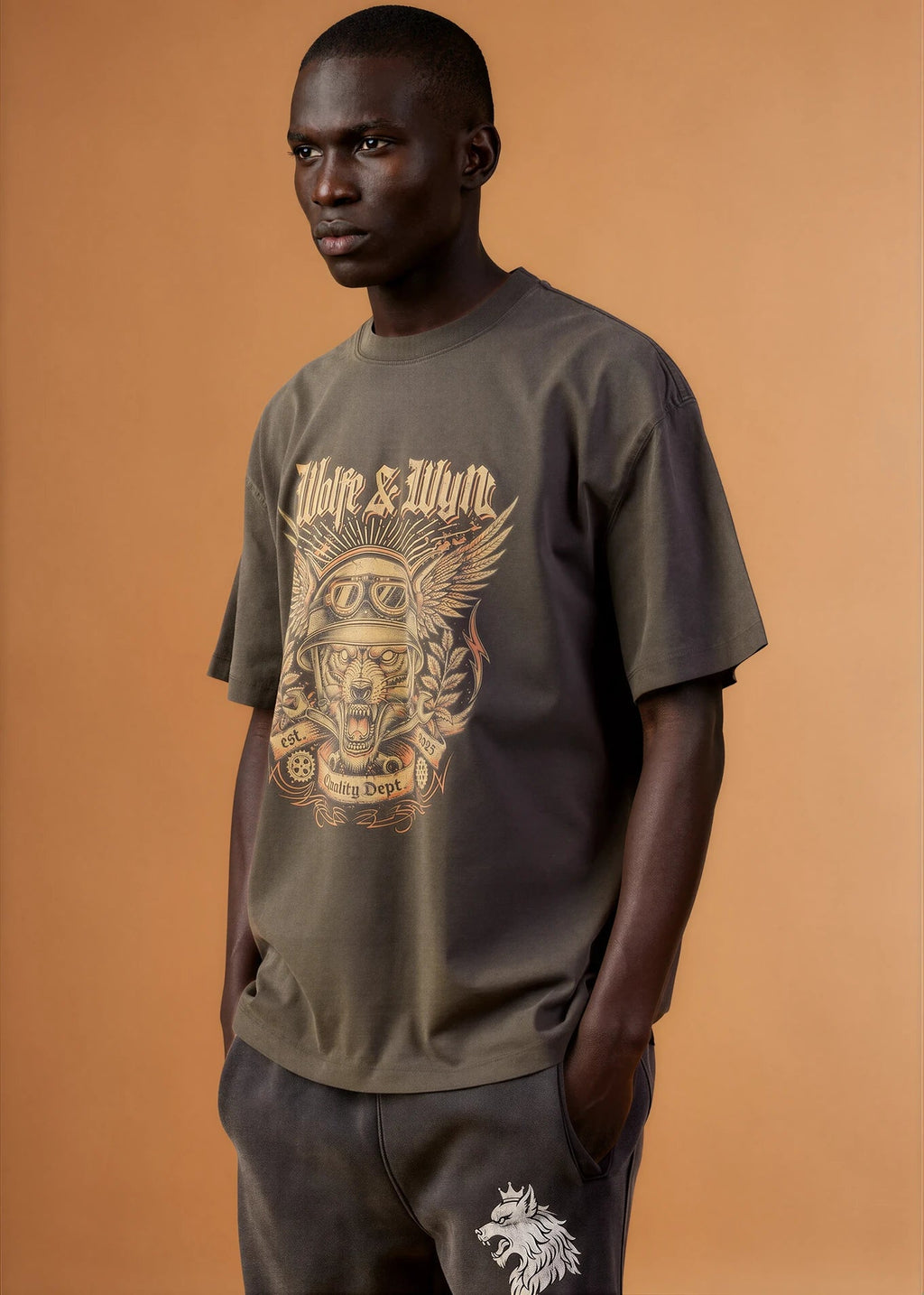 Man wearing a graphic t-shirt with a brand logo on an orange background