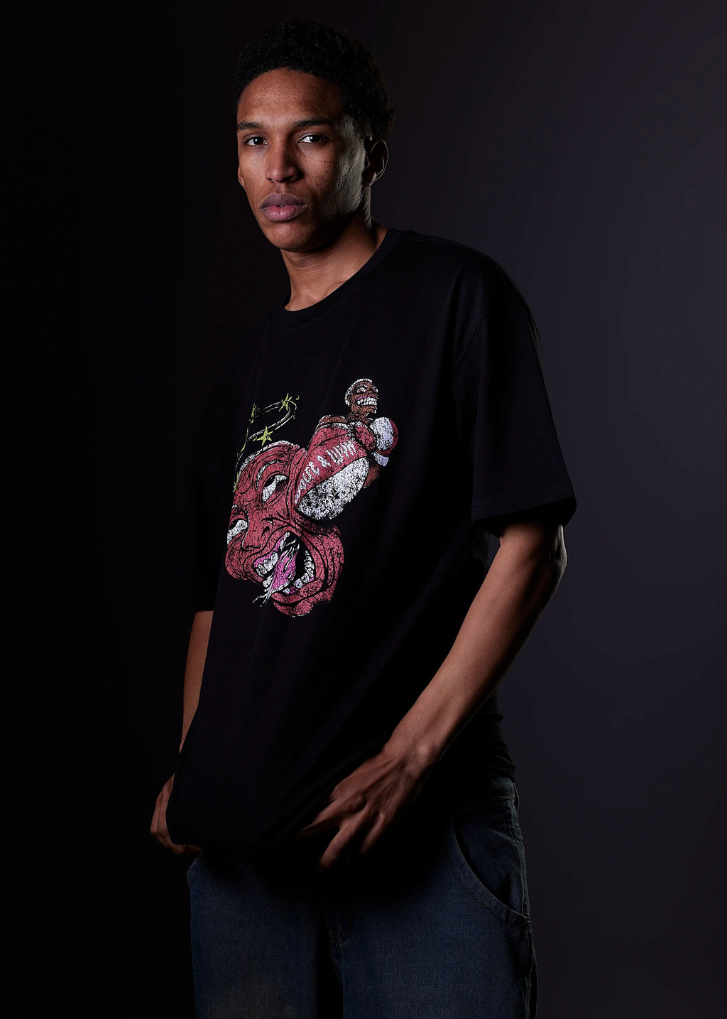 Person wearing a black t-shirt with a colorful graphic design on a dark background