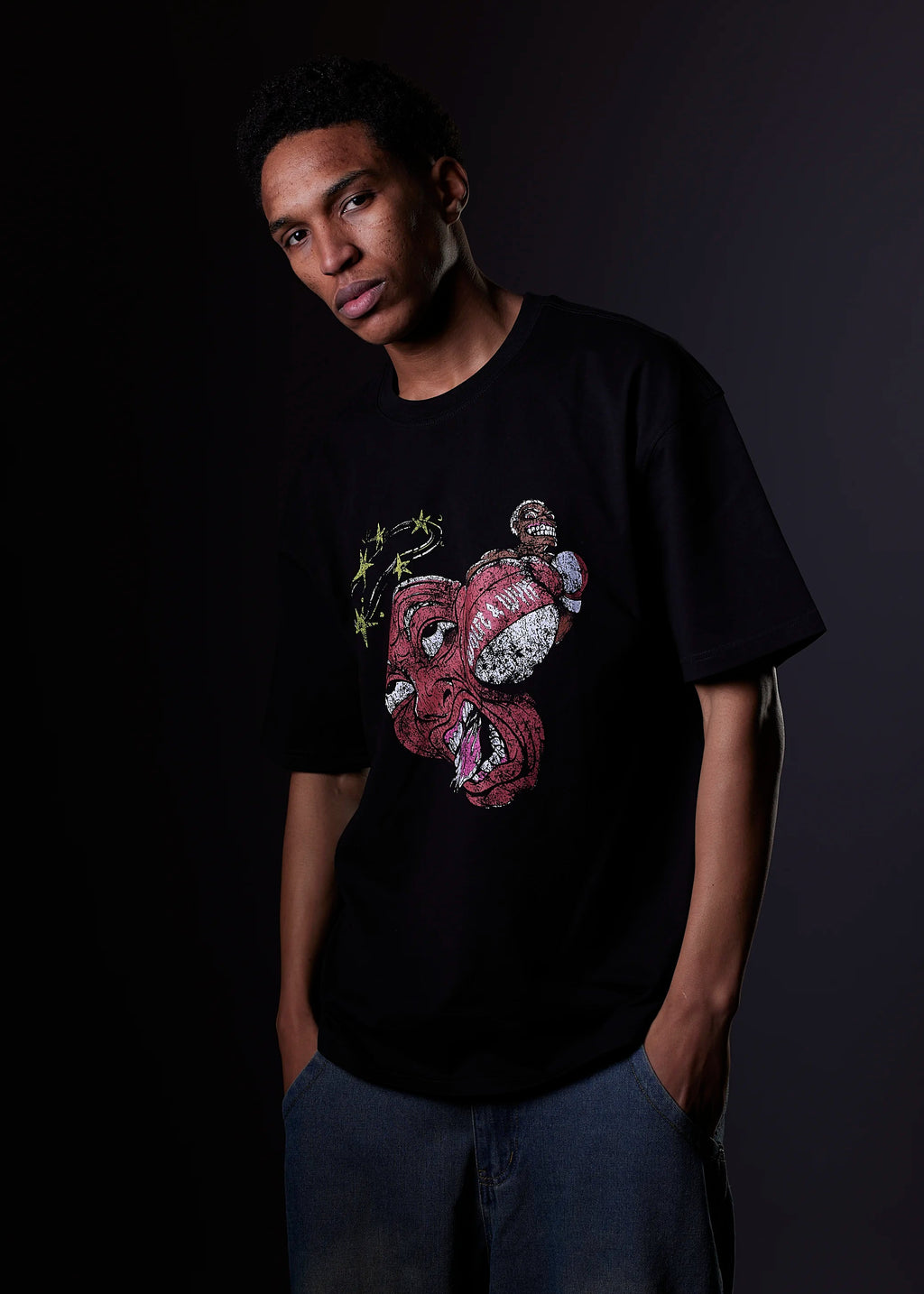 Person wearing a black t-shirt with a colorful graphic design on a dark background