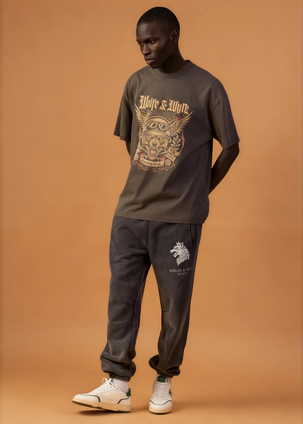 Man wearing a dark green graphic t-shirt and matching pants on a brown background