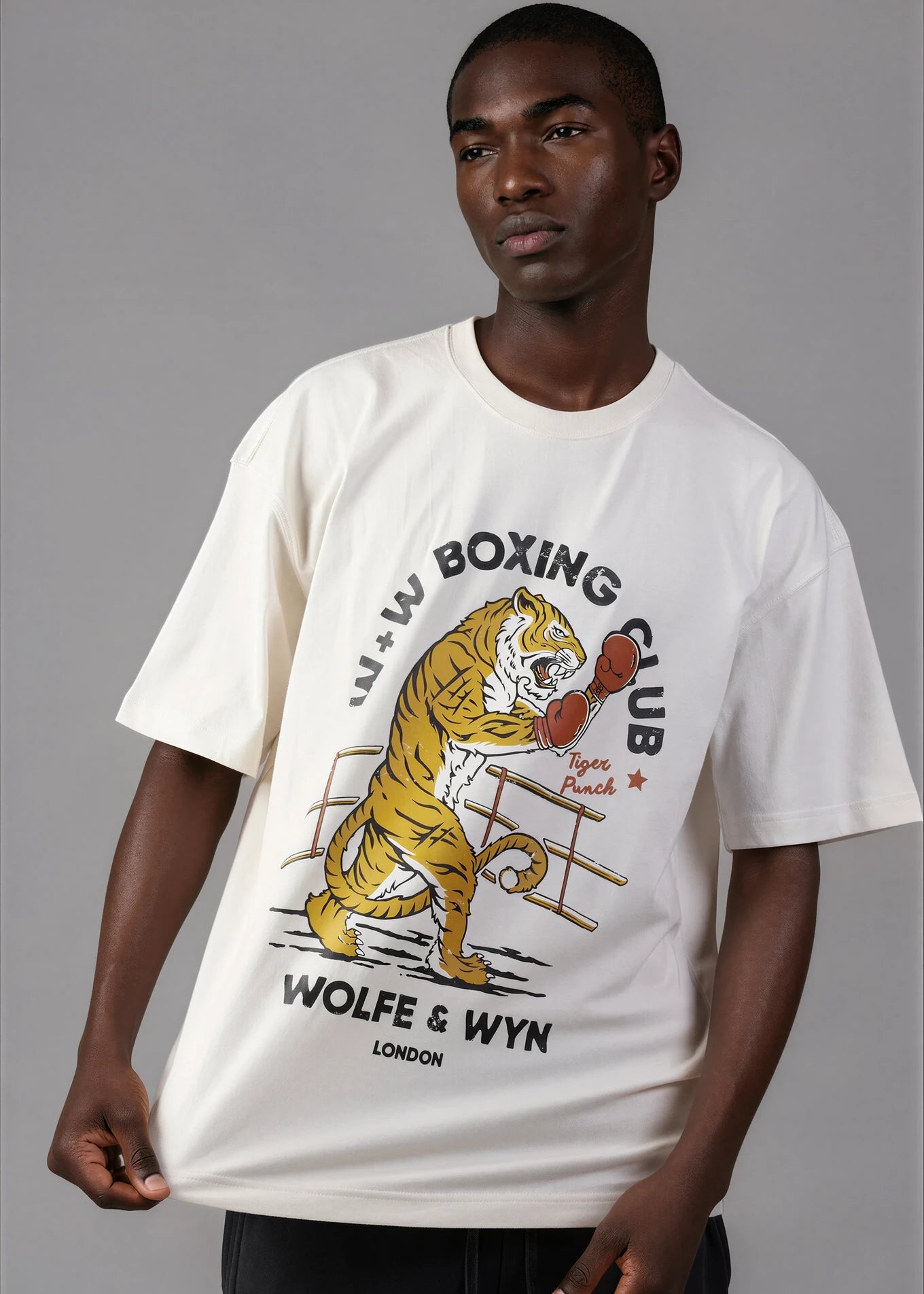 Man wearing a white t-shirt with a tiger graphic and text on a gray background