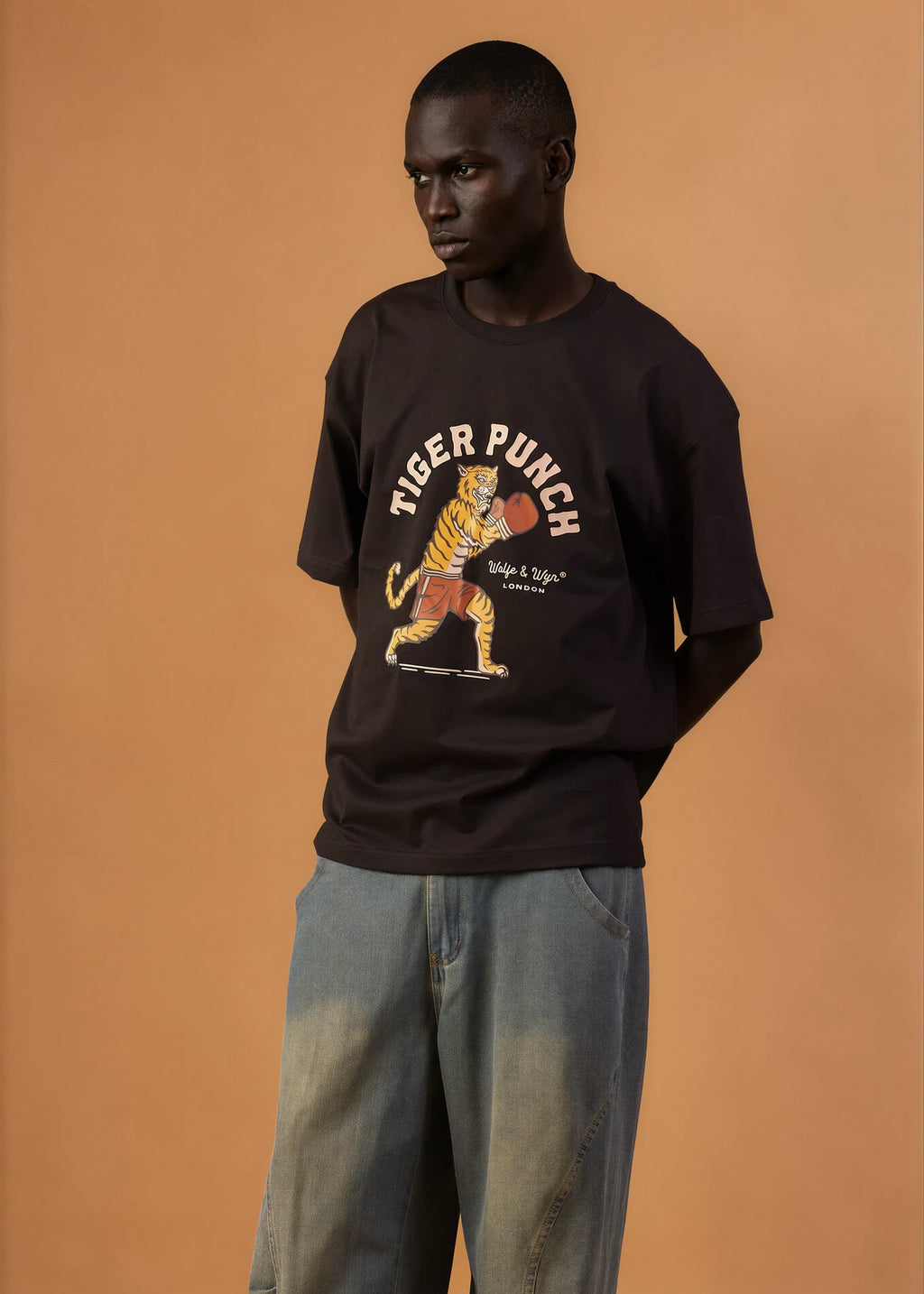 Person wearing a black t-shirt with a tiger graphic and 'Tiger Punch' text on a brown background