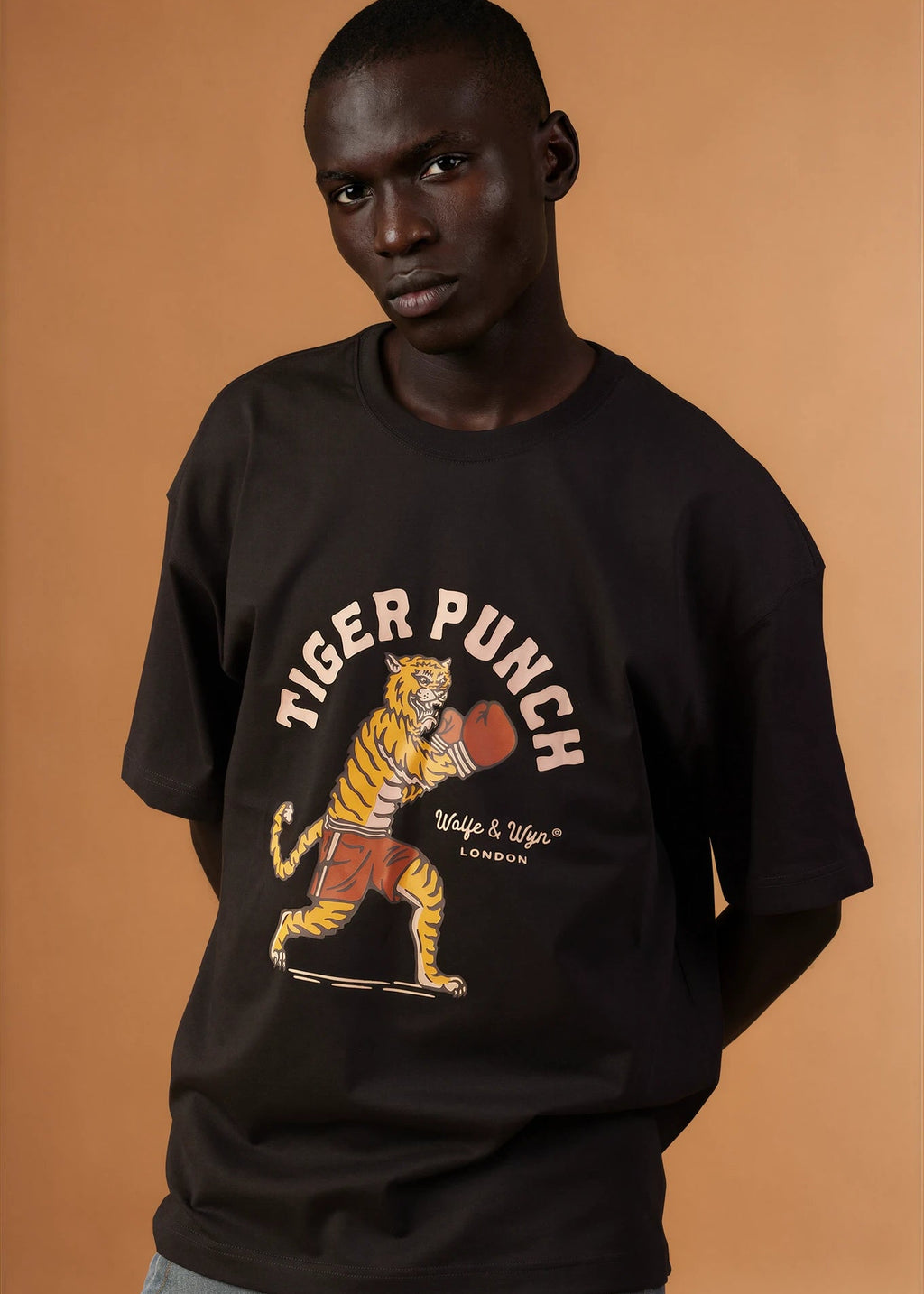 Person wearing a black t-shirt with a tiger graphic and 'Tiger Punch' text on a brown background
