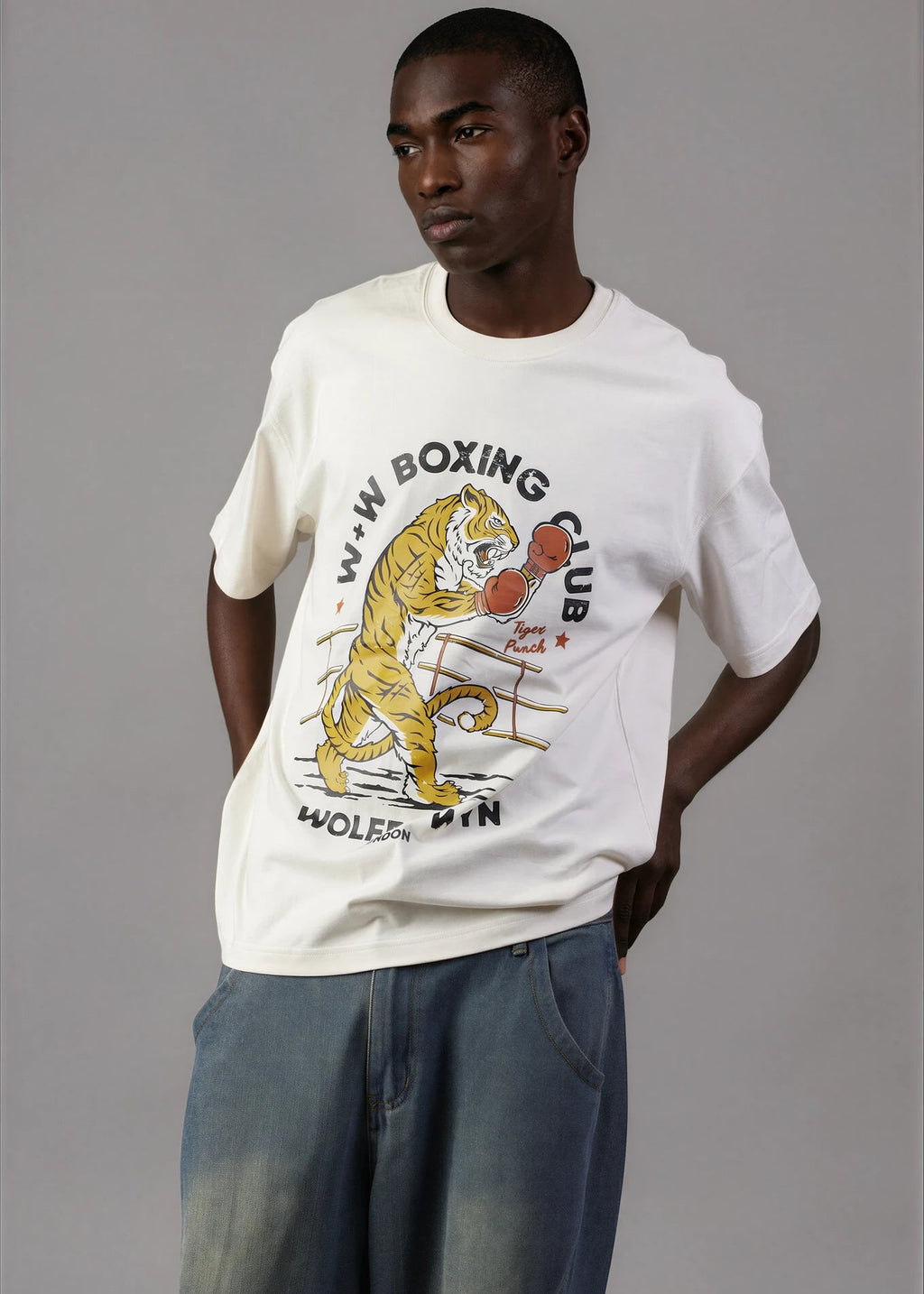 Man wearing a white t-shirt with a graphic design of a tiger boxing, standing against a plain background.