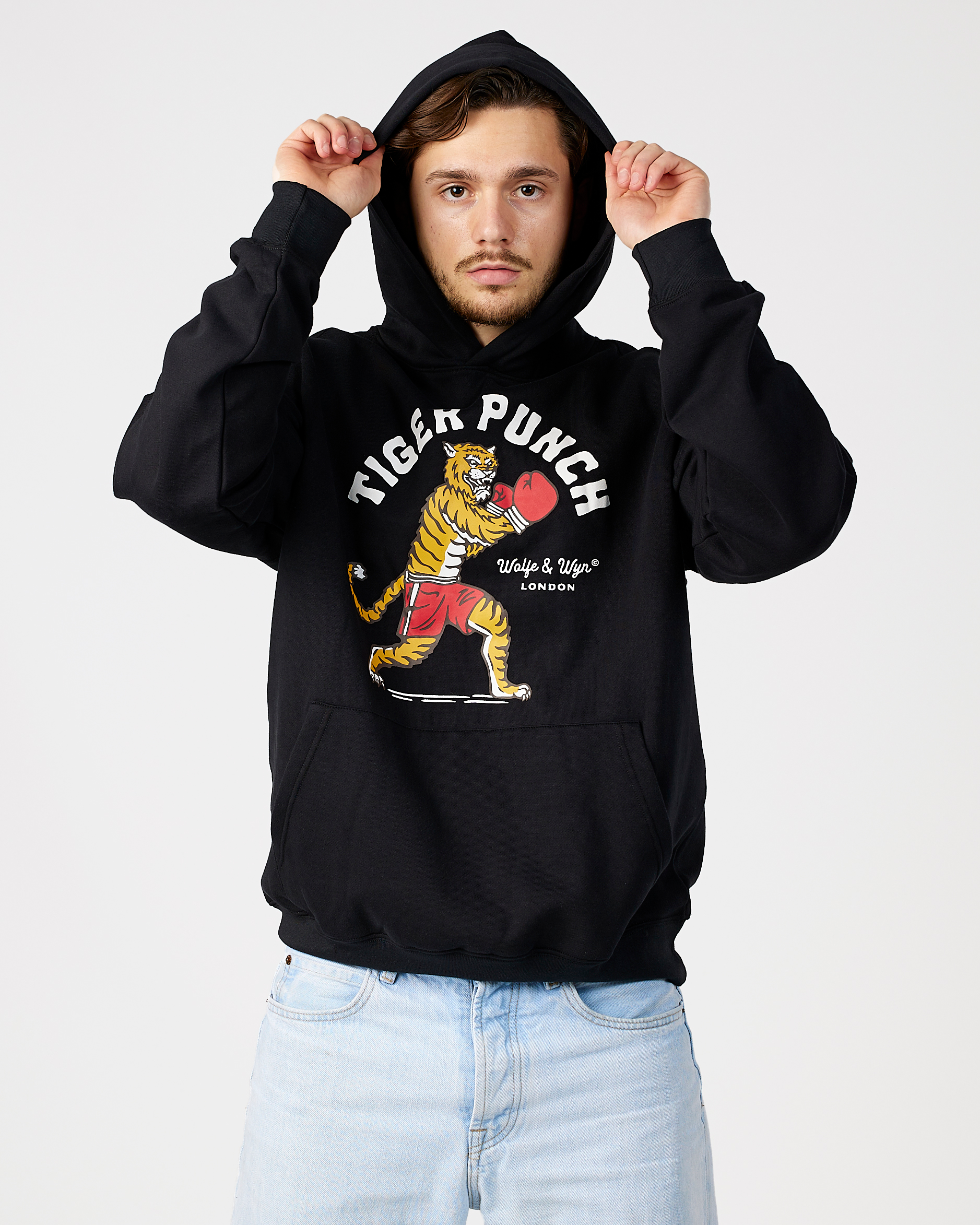 model wearing a black hoodie with a tiger graphic and text on a white background