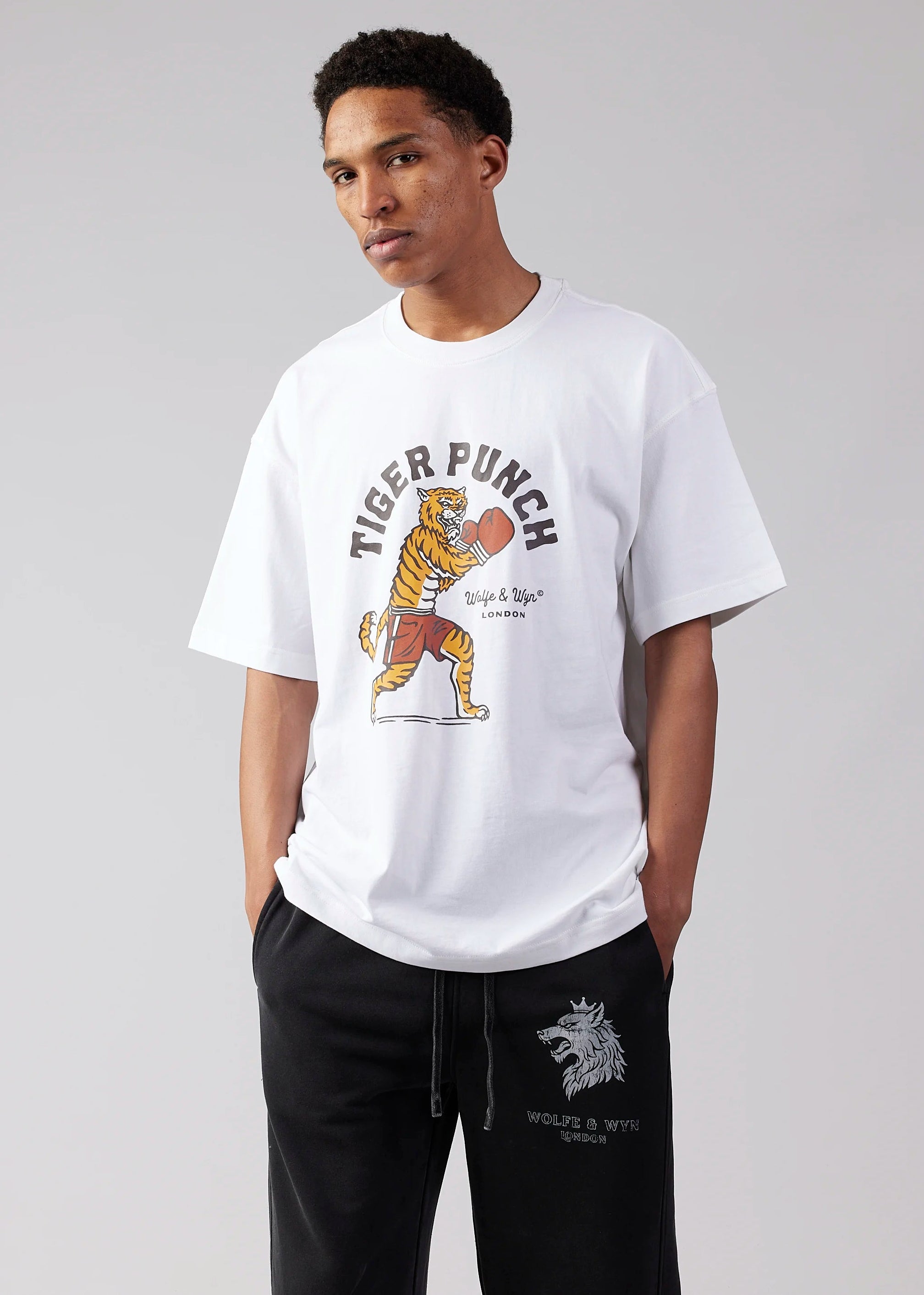 Person wearing a white t-shirt with a tiger graphic and text, standing against a plain background