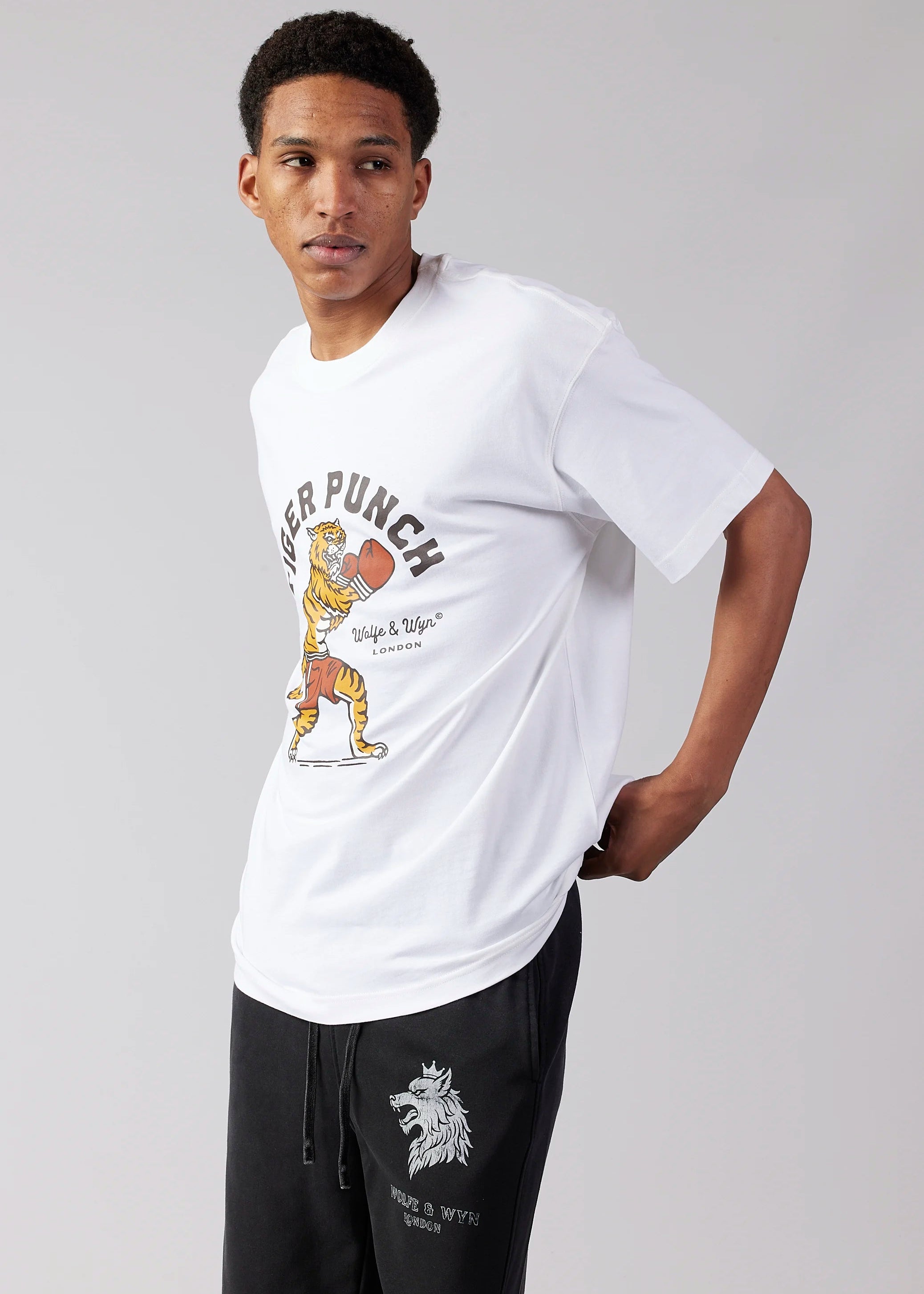 Person wearing a white t-shirt with a graphic design on a plain background