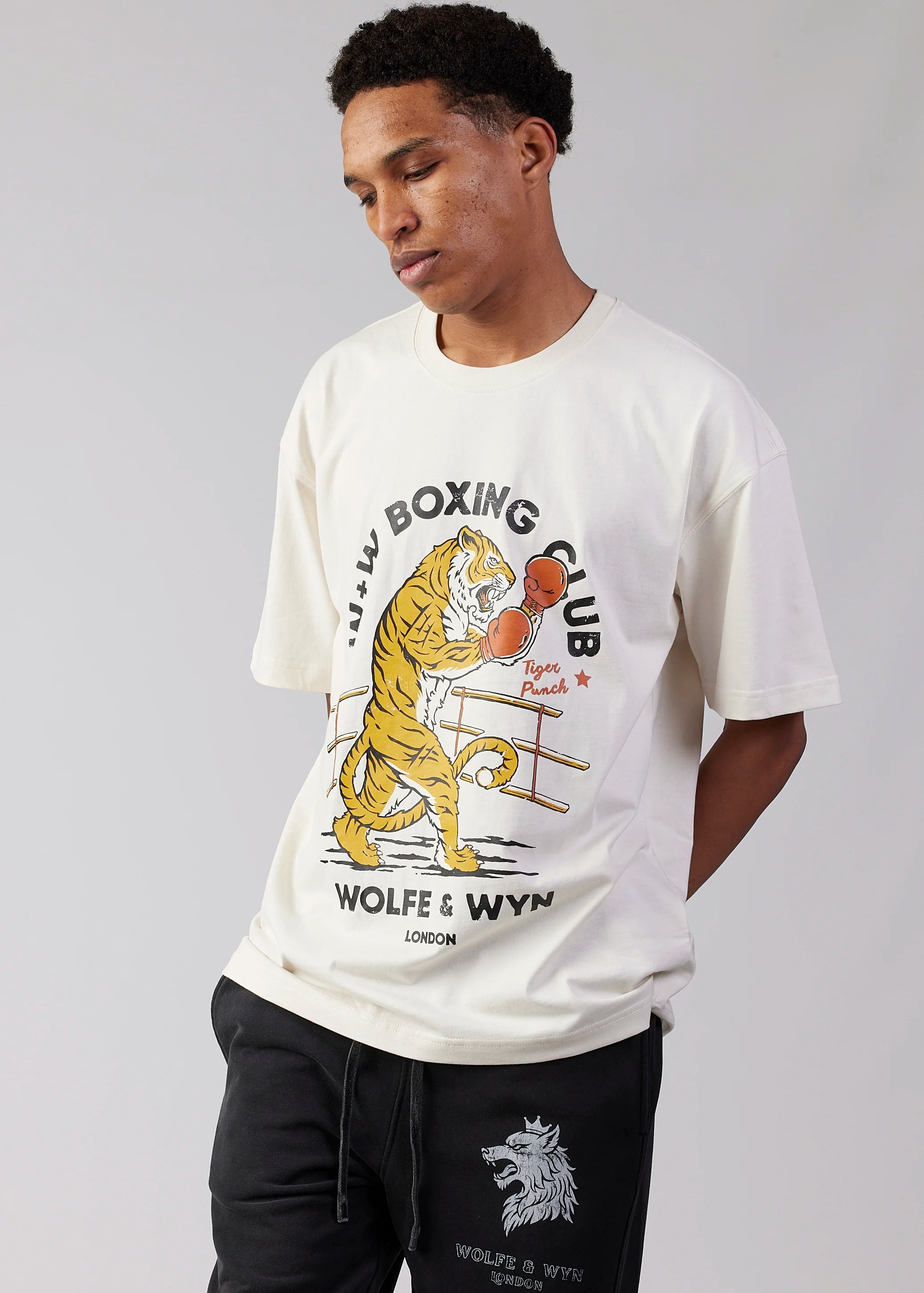 Person wearing a white t-shirt with a boxing graphic and 'Wolfe & Wyn' branding.
