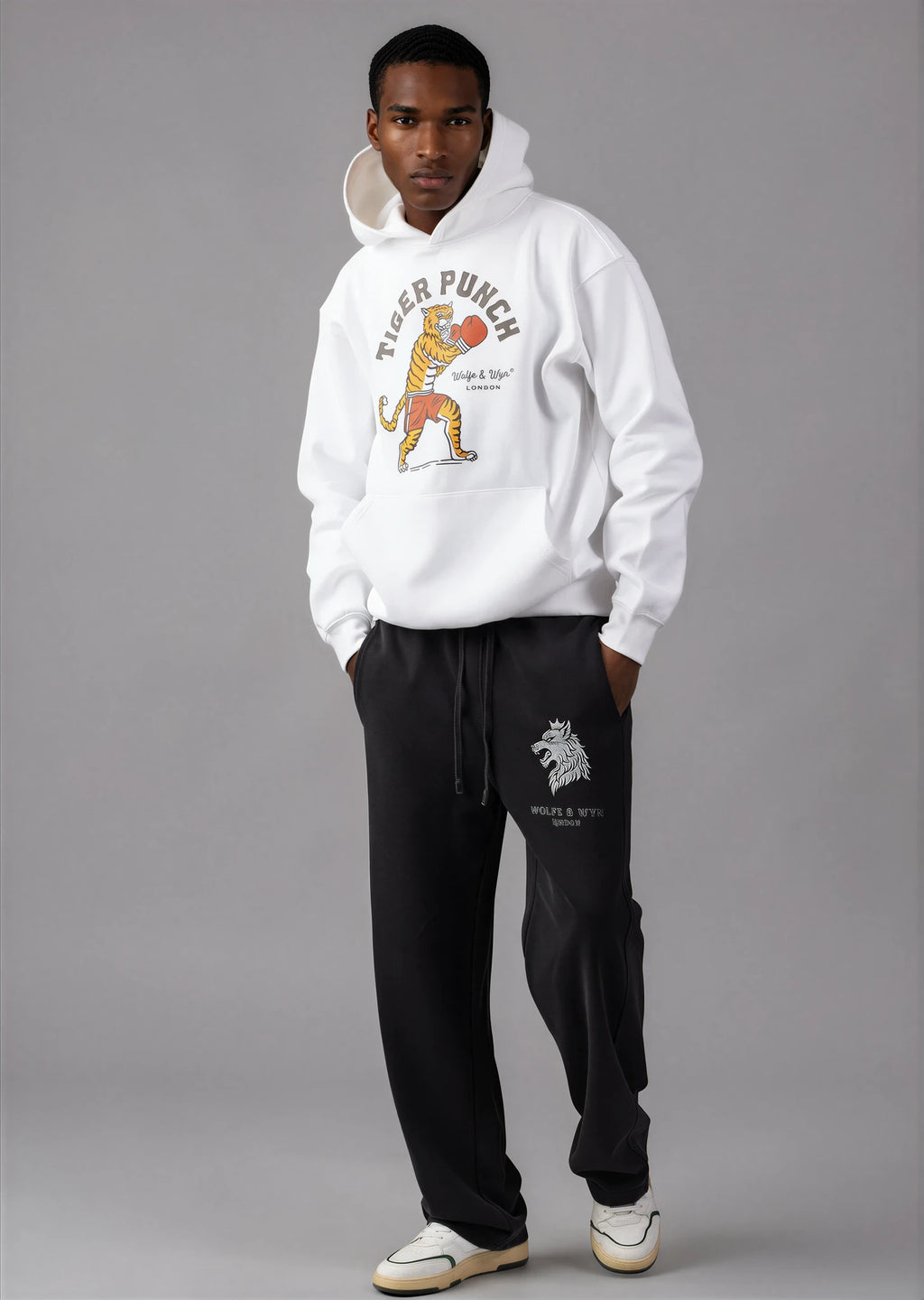 Person wearing a white hoodie with a tiger graphic and black pants on a gray background