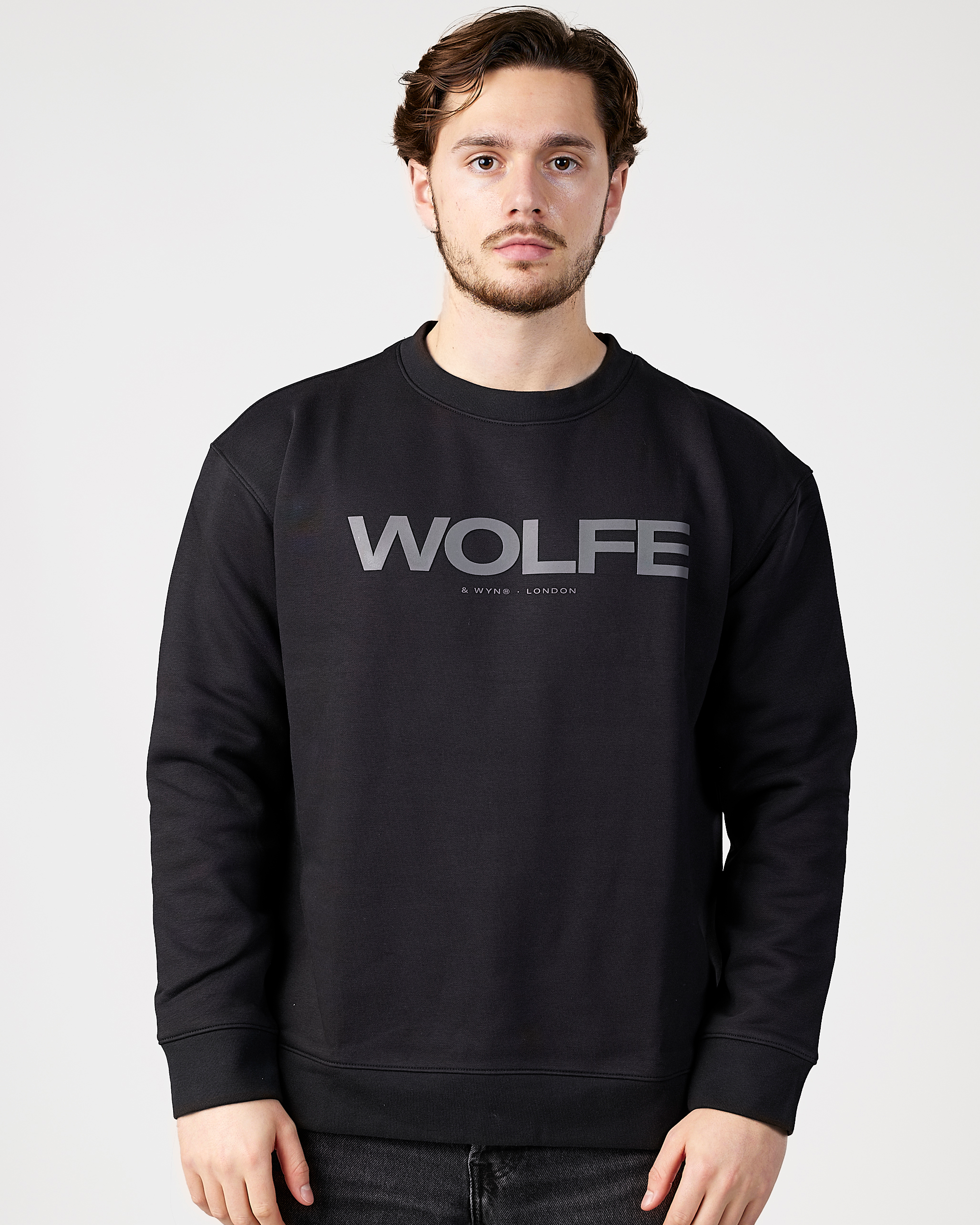 Model wearing a black sweatshirt with 'WOLFE' branding on a light gray background